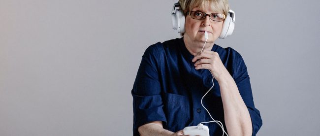 A person seen with the plastic paddle on their tongue and wearing headphones