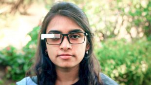 A woman seen wearing glasses with TranscribeGlass attached to them.