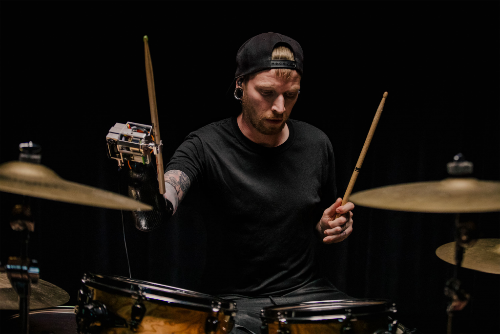 Jason Barnes playing drums wearing his AI powered robotic prosthetic arm