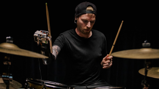 Jason Barnes playing drums wearing his AI powered robotic prosthetic arm