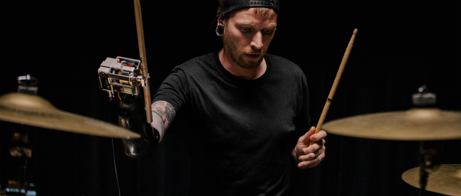 Jason Barnes playing drums wearing his AI powered robotic prosthetic arm