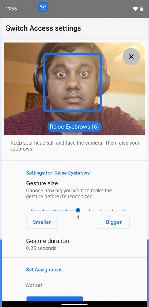 A person setting up their android phone for facial gestures. Screen shows camera enabled with a blue box around his face with raised eyebrows with label “raise eyebrows”. There are some settings options in the bottom half.