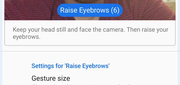 A person setting up their android phone for facial gestures. Screen shows camera enabled with a blue box around his face with raised eyebrows with label “raise eyebrows”. There are some settings options in the bottom half.