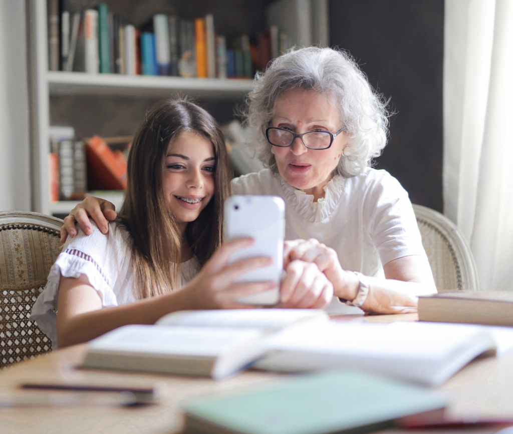 a young girl showing something to an elderly woman on her phone