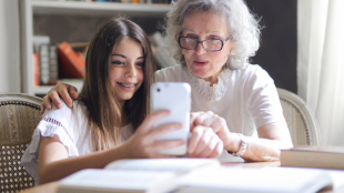 a young girl showing something to an elderly woman on her phone