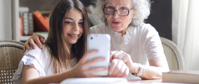 a young girl showing something to an elderly woman on her phone