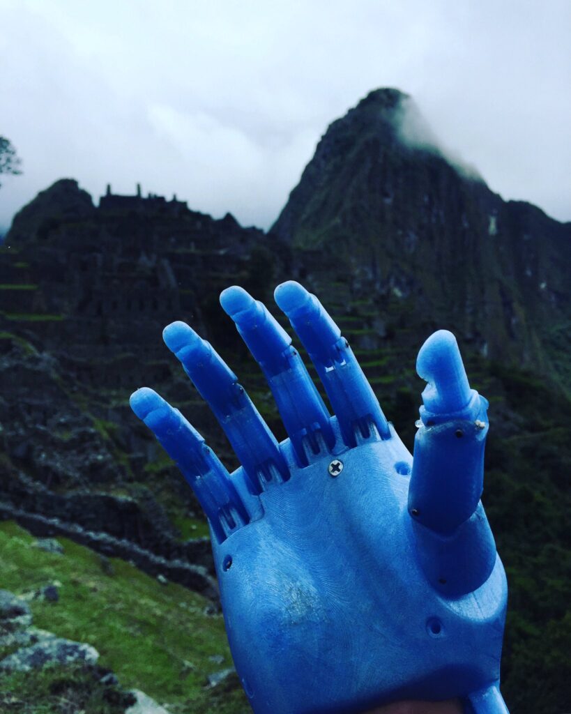 Photo of Enzo’s prosthetic arm made out of melted plastic bottles. In the background is Machu Pichu.