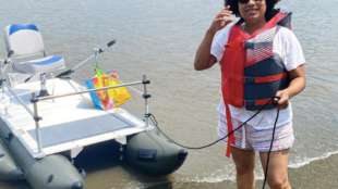 Yvonne standing next to a boat on a beach.