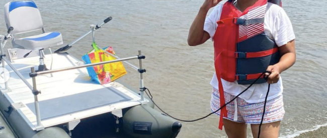 Yvonne standing next to a boat on a beach.