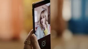 close up of a person holding their phone in their hand with the screen facing them. Guided Frame is enabled and it has a circle around their face indicating a well framed selfie