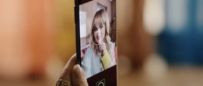 close up of a person holding their phone in their hand with the screen facing them. Guided Frame is enabled and it has a circle around their face indicating a well framed selfie