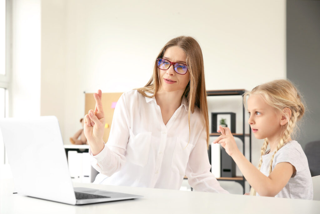 Mother teaching her deaf mute daughter to use sign language at home