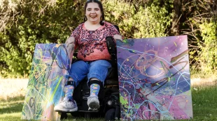 Kaya Eccles smiles as she poses for photos with two of her paintings in Logan on Wednesday, July 12, 2023