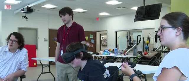 A kid in black shirt plays VR games while three others look at his game.