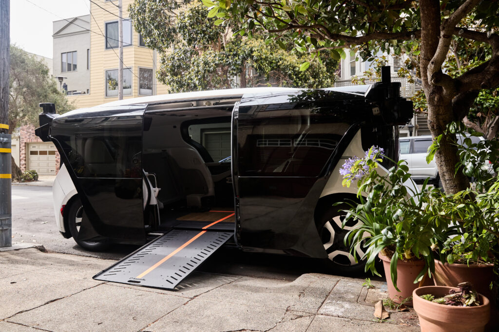 Photo of cruise wheelchair accessible robotaxi with the wheelchair ramp extended out to a sidewalk.