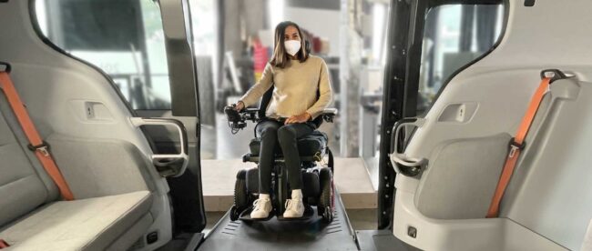 a woman in a powered wheelchair and wearing a mask entering the cruise wheelchair accessible robotaxi