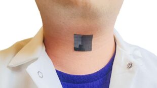 The image shows a person wearing a white shirt and a blue undershirt with a small, black, square bioelectronic device adhered to their neck. The placement on the neck suggests it is positioned over the larynx, aligning with the technology designed to capture muscle movements and translate them into speech.