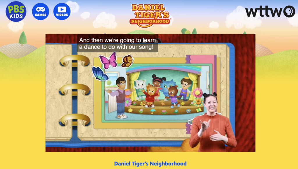 The image is a screenshot from the PBS Kids website featuring the show "Daniel Tiger's Neighborhood". It displays an American Sign Language (ASL) interpreter in the foreground on the right, wearing a coral-colored top and smiling while signing. The background shows an animated scene from the show with the characters on a stage, framed by a colorful, storybook-like design with the caption "And then we're going to learn a dance to do with our song!" The PBS Kids, Games, and Videos icons are visible at the top, and the WTTW logo is in the top right corner. The layout is vibrant and child-friendly, aimed at combining visual storytelling with ASL to make the content accessible to deaf and hard-of-hearing children.