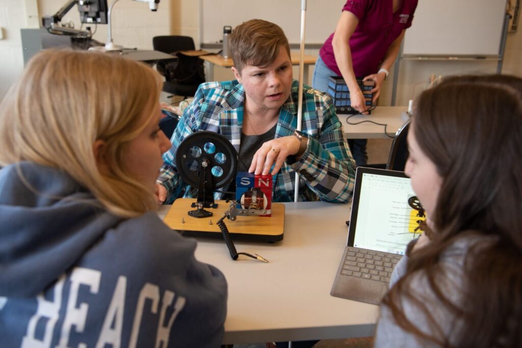 Dr. Natalie Shaheen, seen interacting with two students in a lab.