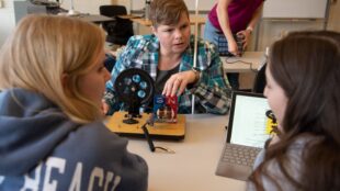 Dr. Natalie Shaheen, seen interacting with two students in a lab.