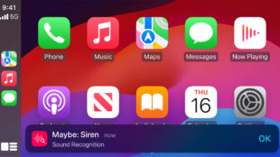 The image shows the CarPlay interface. Various app icons such as Phone, Music, Maps, Messages, and Now Playing are visible on the screen. At the bottom of the screen, a notification banner with the title "Maybe: Siren" is displayed, indicating the Sound Recognition feature. The notification suggests that a siren sound has been detected, providing an alert for the user.