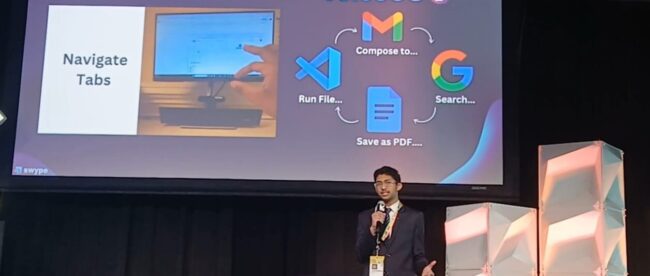 Young entrepreneur Dhanvin Ganeshkumar, dressed in a suit, presents on a stage at SXSW EDU. Behind him, a presentation slide for his solution, 