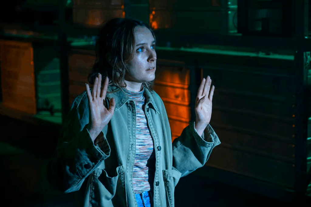 Actress Rose Ayling-Ellis in a what seems like a dark alley. Both her hands are up.