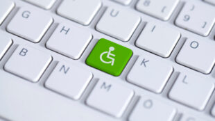Green key with wheelchair icon on white laptop keyboard. Accessibility disability computer symbol
